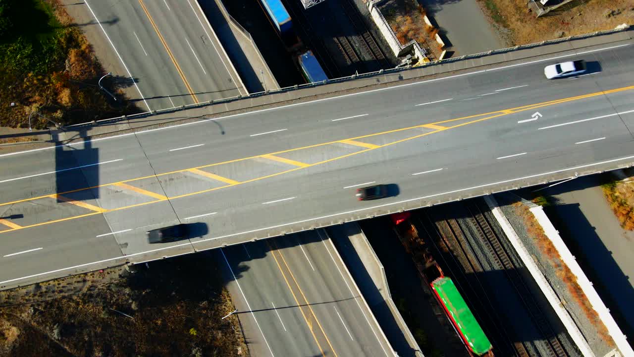 화창한 날에 기차와 차량이 거리를 이동하는 캐나다 bc 주 캠룹스의 1번 고속도로 교량과 옐로우헤드 고속도로의 정상 속도 조감도 회전 왼쪽 드론 샷