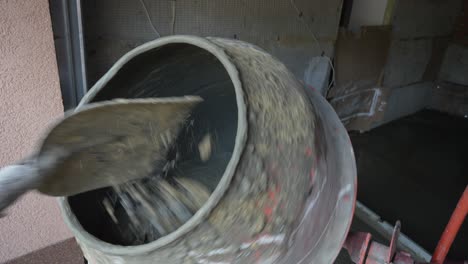 worker pours rubble and sand in concrete mixer at construction site with shovel