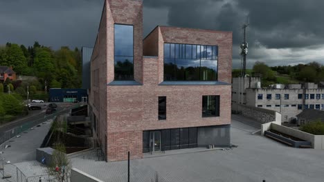 peace campus, county monaghan, ireland, april 2024. drone hovers infront of the facade of the monaghan county museum building against a backdrop of dark moody clouds.