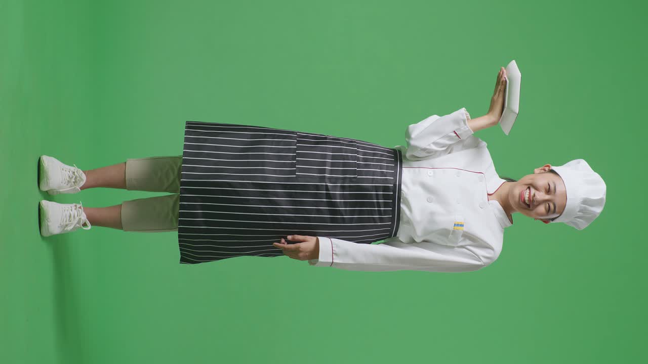 Full Body Of Asian Woman Chef Holding A Dish And Smiling To Camera While Standing In The Green Screen Background Studio