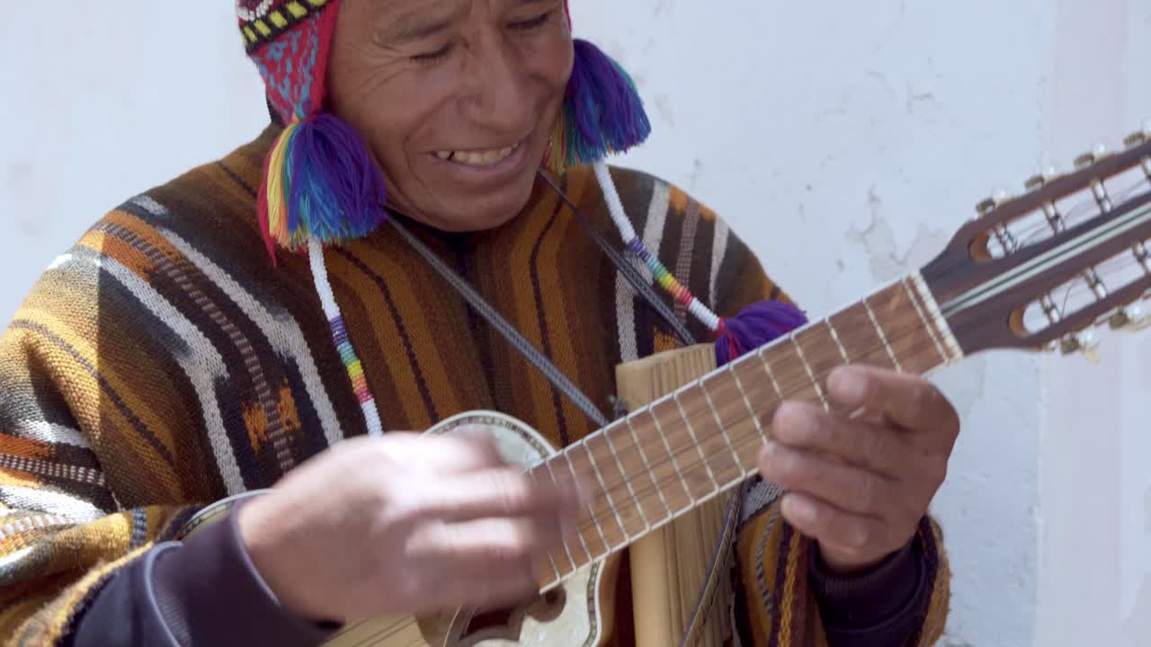 Native street performer, busker, plays charango and pan flute, Cuzco, Peru, close up