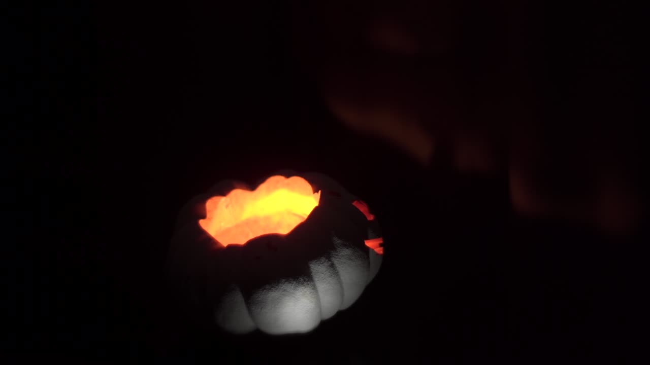 A scary pumpkin with glowing eyes circling around, lightly lit from below for a dramatic effect