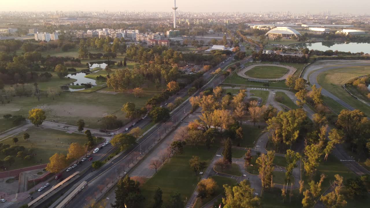 sobrevuelo aéreo roca park y city park durante la puesta de sol en buenos aires - centro y torre en segundo plano