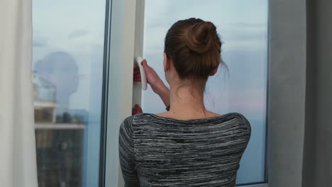 silueta de una mujer joven que se acerca a la ventana desvelando las cortinas y mirando por la ventana. disfrutando de la vista afuera