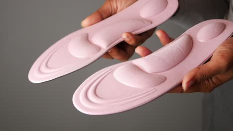 woman holding pink shoe insoles