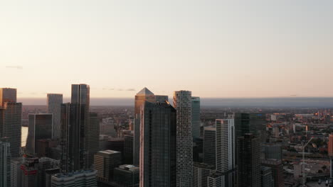 Vuela-Alrededor-De-Altos-Rascacielos-Que-Se-Elevan-Por-Encima-De-Otros-Edificios-En-La-Ciudad.-Efecto-De-Paralaje-Imágenes-Aéreas-Nocturnas-De-Canary-Wharf.-Londres,-Reino-Unido