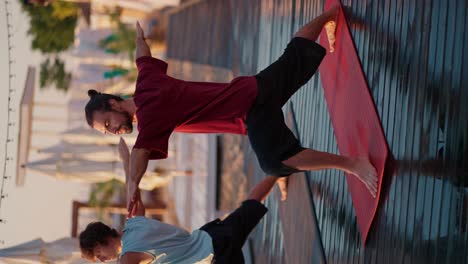 Two-guys-stretched-their-arms-out-to-the-sides-and-are-doing-yoga-on-special-red-mats-on-the-beach.-Peace-of-mind-and-body.-Harmony,-zen-style