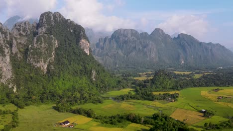 Aerial-view-of-farm-fields-and-rock-formations-in-Vang-Vieng,-Laos