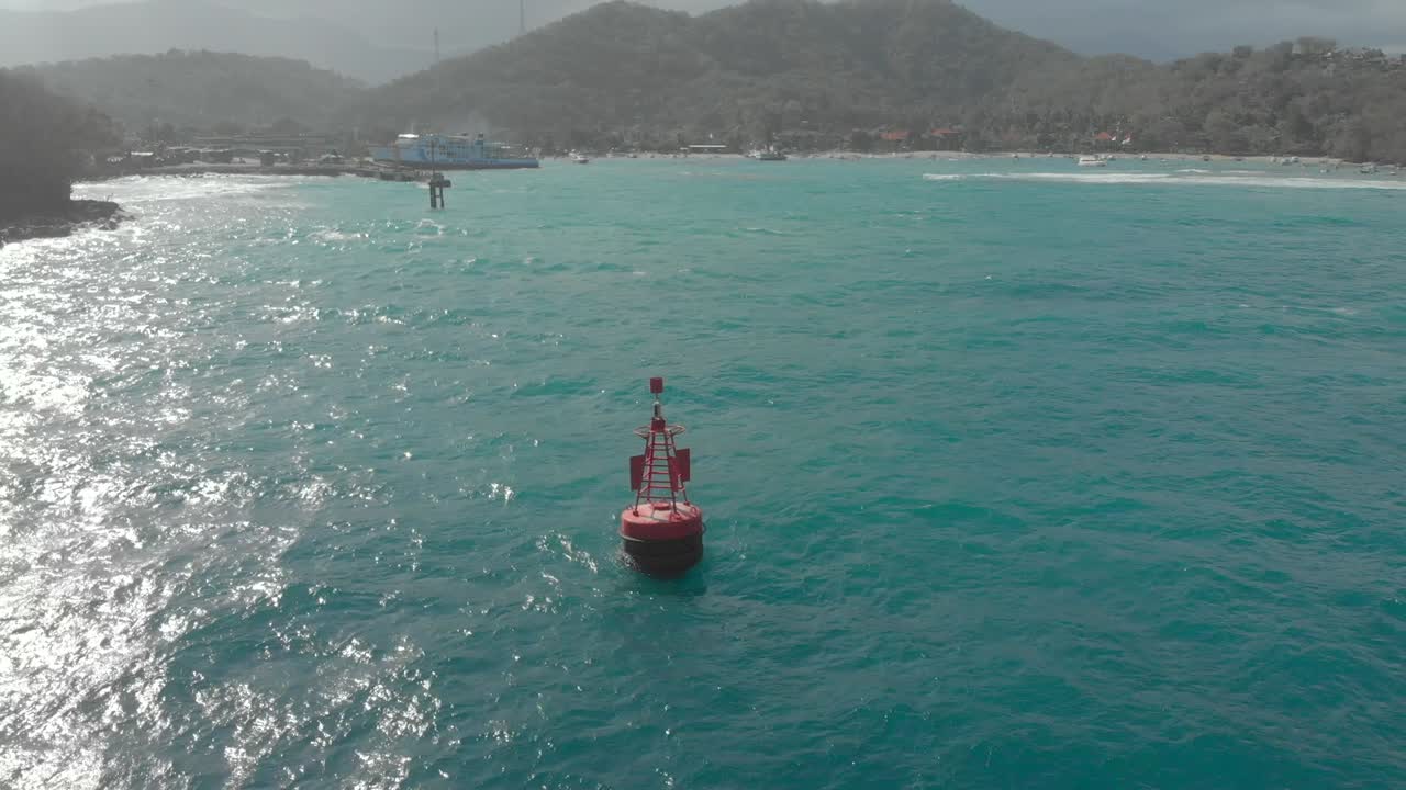 Aerial shot of a red buoy at the entrance to the port of Padang bai, Bali, Indonesia
