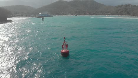 aerial shot of a red buoy at the entrance to the port of padang bai, bali, indonesia