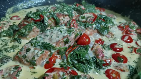 salmone, cotto in padella e accompagnato da spinaci cremosi e pomodori, bollito delicatamente in una padella a fuoco medio, bollendo con una lenta grazia bollente