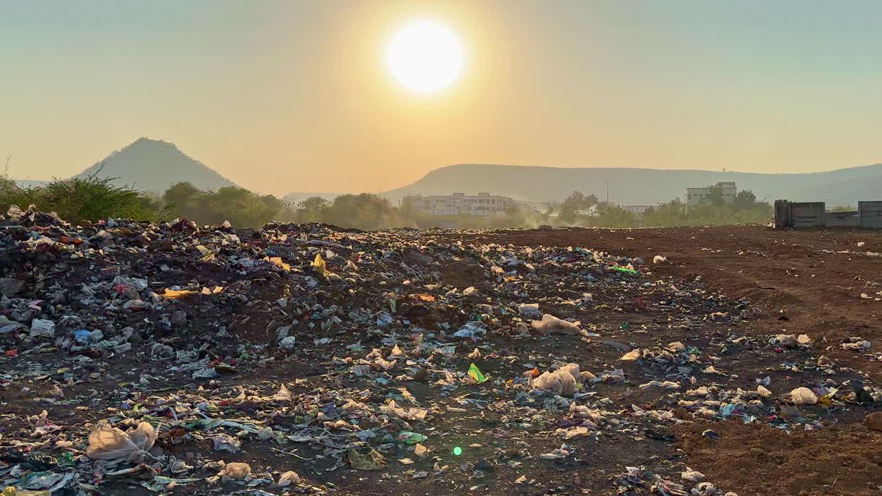 sunset at the landfill site or dumping yard filled with waste plastic and garbage.