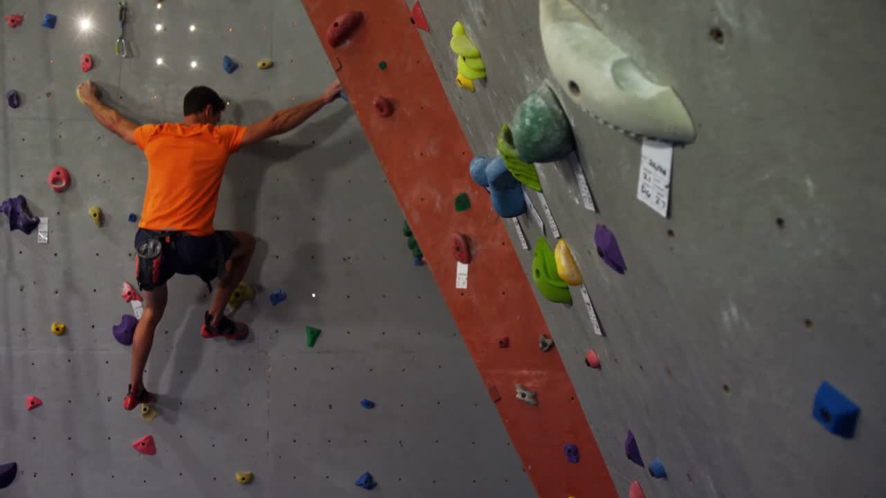 Man climbing artificial wall at bouldering gym 4k