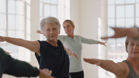 yoga class of healthy mature women practicing warrior pose enjoying morning physical fitness workout in studio