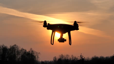 drone silhouette flying in front of sun during sunset