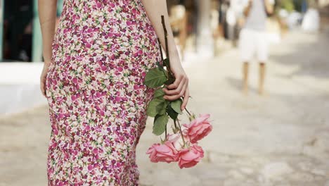 cropped view of a girl walking by the street with pink roses