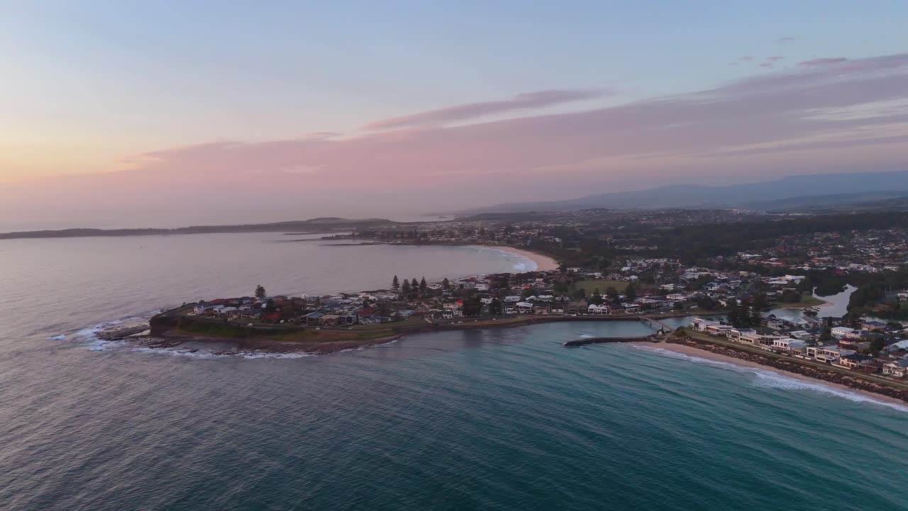 Coastal homes and sweeping ocean at Barrack Point captured in early evening light, aerial tracking overview