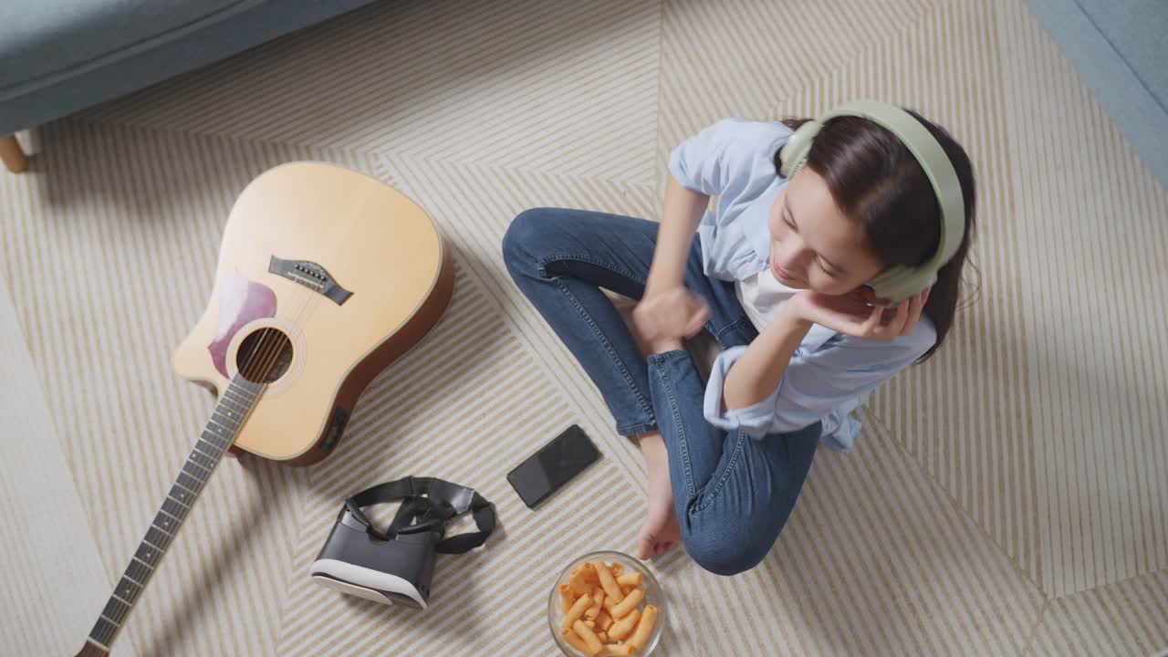 Adolescente relajándose en casa con música y aperitivos.