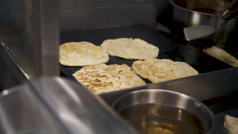 vendor frying roti frata street food on griddle at tekka centre market in singapore