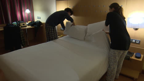 young people making bed in a hotel room