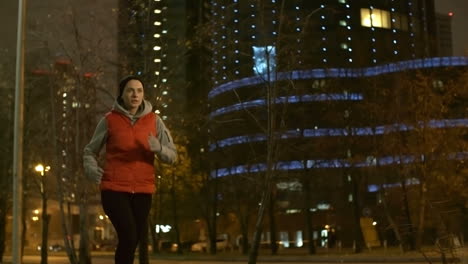 woman in sportswear running in the city at night in winter