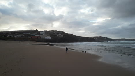 Toma-Aérea-De-Una-Mujer-De-Mediana-Edad-Caminando-Durante-La-Puesta-De-Sol-En-La-Playa-De-Boca-Barranco-En-La-Ciudad-De-Galdar,-En-La-Isla-De-Gran-Canaria