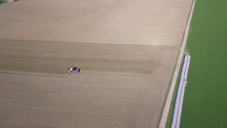 Toma-Aérea-De-Drones-Del-Tractor-Trabajando-Y-Cultivando-Tierras-Agrícolas