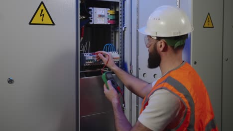 el electricista está comprobando el voltaje eléctrico dentro del panel eléctrico por multimetro