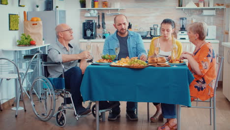 abuelo discapacitado y familia cenando