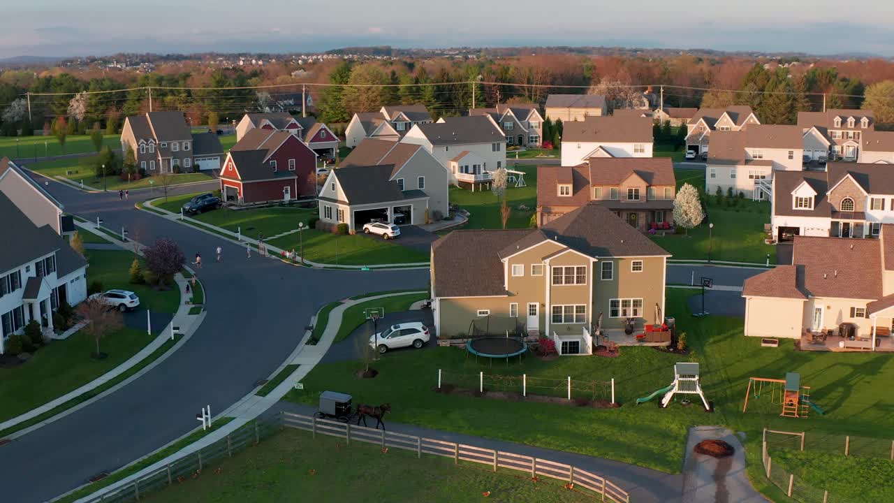 Un cheval et un buggy Amish entrent dans une allée au milieu d'un lotissement résidentiel de banlieue.