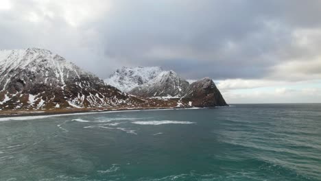 Vista-Aérea-Inversa-Del-Agua-Del-Océano-Y-La-Costa-De-Las-Montañas-Cubiertas-De-Nieve---Drone-4k