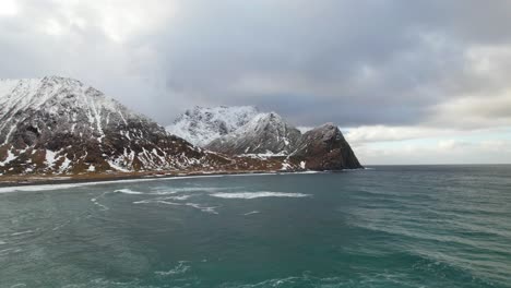 vista aérea al revés del agua del océano y la costa de las montañas cubiertas de nieve - dron 4k