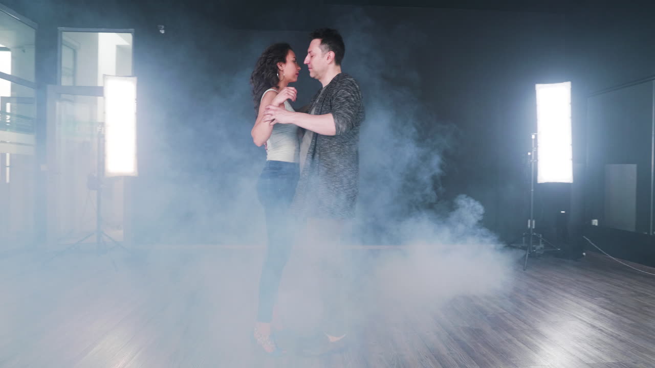 Couple dancing in a smoke-filled dance studio