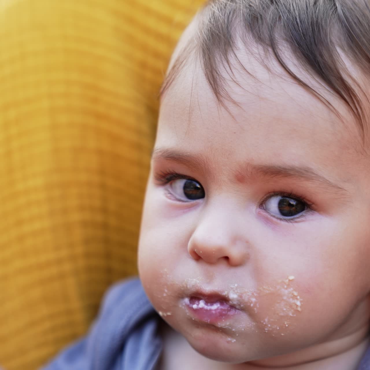 Nice Caucasian toddler eating porridge willingly. Portrait of a baby with porridge on his face looking at camera. Close up