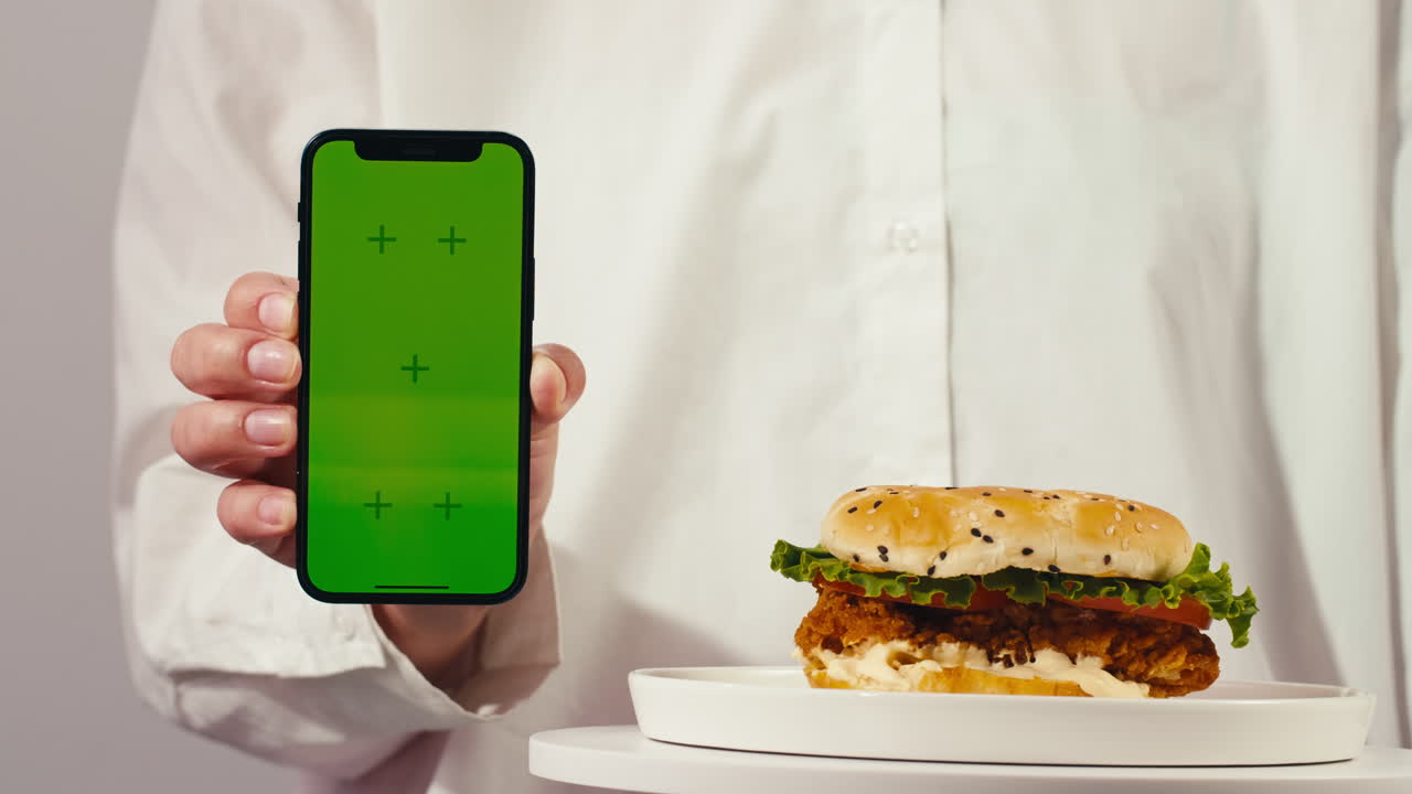 Person holding a green screen phone displaying food photo