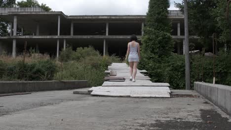 unrecognizable woman enters abandoned water park. static view