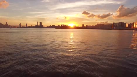 Footage displays water, sea and city in sundown and sunset during evening and night time while sun is setting and sundown. The aerial view is done while drone is moving over water slowly in 4K.