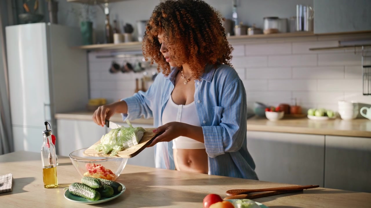 Futura mamma che affetta cavolo in cucina. Donna incinta che prepara l'insalata a casa