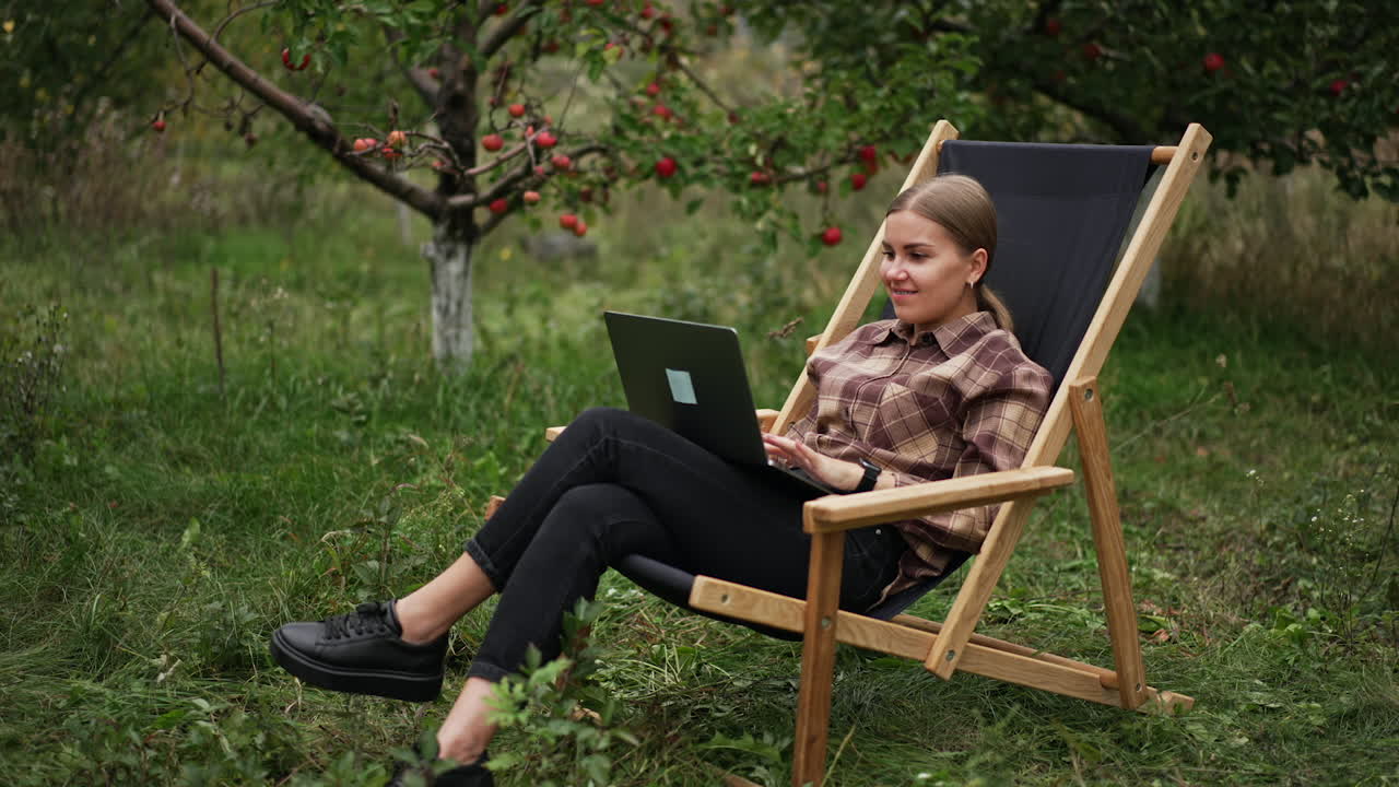 женщина работает на ноутбуке в яблочном саду