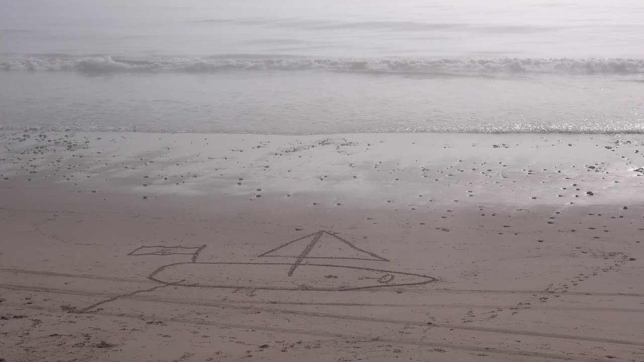 해변의 모래에 범선이 그려져 있다