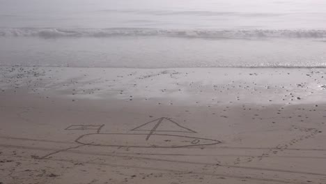 a sailboat is drawn in the sand on a beach