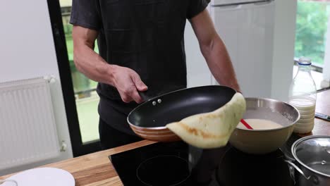 person flipping pancakes in a home kitchen