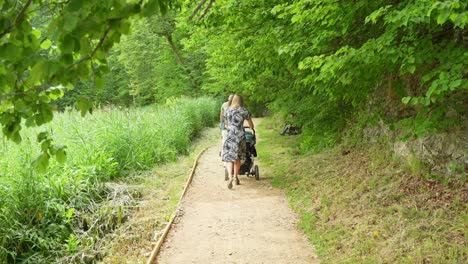 mother pushing baby cart stroller: blonde woman's loving gesture, no faces shown