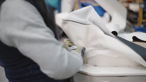 shot of a worker fitting, cutting and stapling, fabric around a preformed hard shape, inside workshop.
