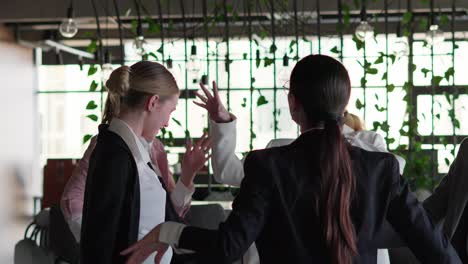 Group-of-happy-businesswomen-in-business-clothes-dancing-during-a-meeting-and-a-short-break-at-work-in-a-modern-office