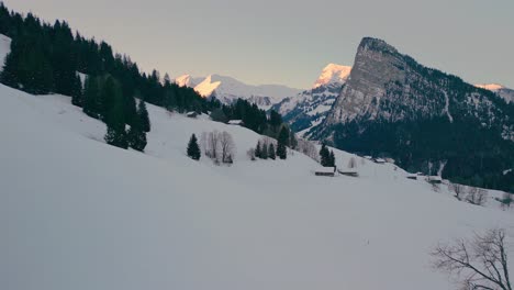 Drone-flying-over-a-snowy-winter-landscape-in-the-Swiss-alps-in-the-early-morning