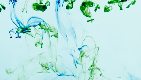 4k footage of green and blue colorful ink drops in water, isolated abstract background. pouring ink in water. underwater paint mix. slow psychedelic dye swirls, colored smoke explosion. splashing, floating liquid