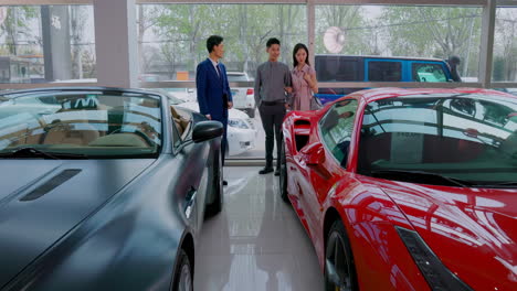 couple with attractive auto dealer in a suit presenting new car model to his client