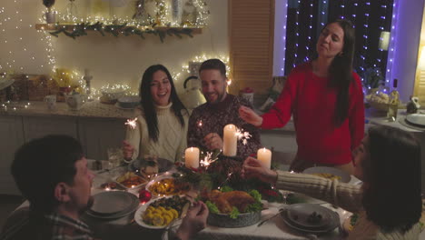 grupo de amigos felices divirtiéndose con bengalas durante la cena de navidad en casa 1