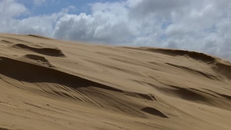 increíble primer plano de cámara lenta de viento que sopla arena de la parte superior de una duna de arena